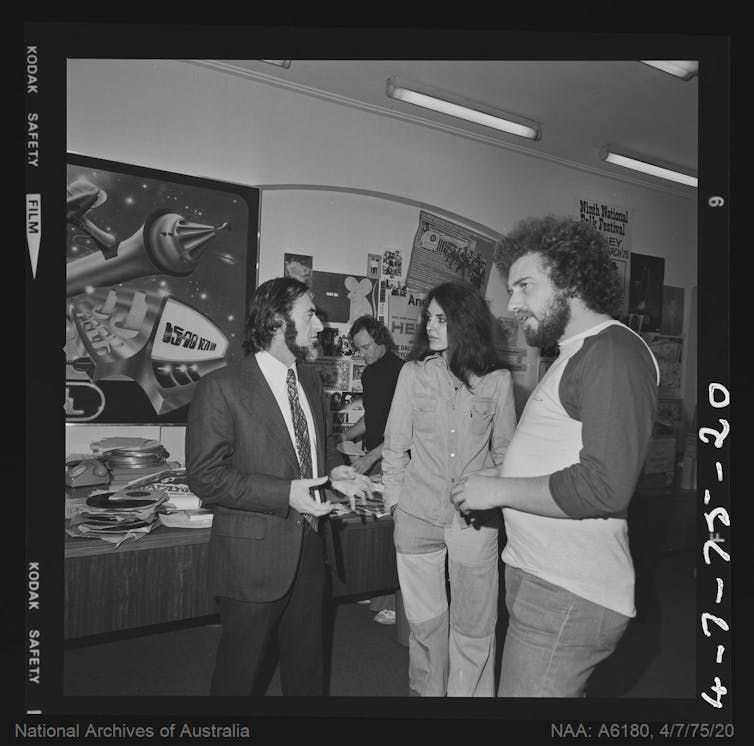 An older man and three young people talk.