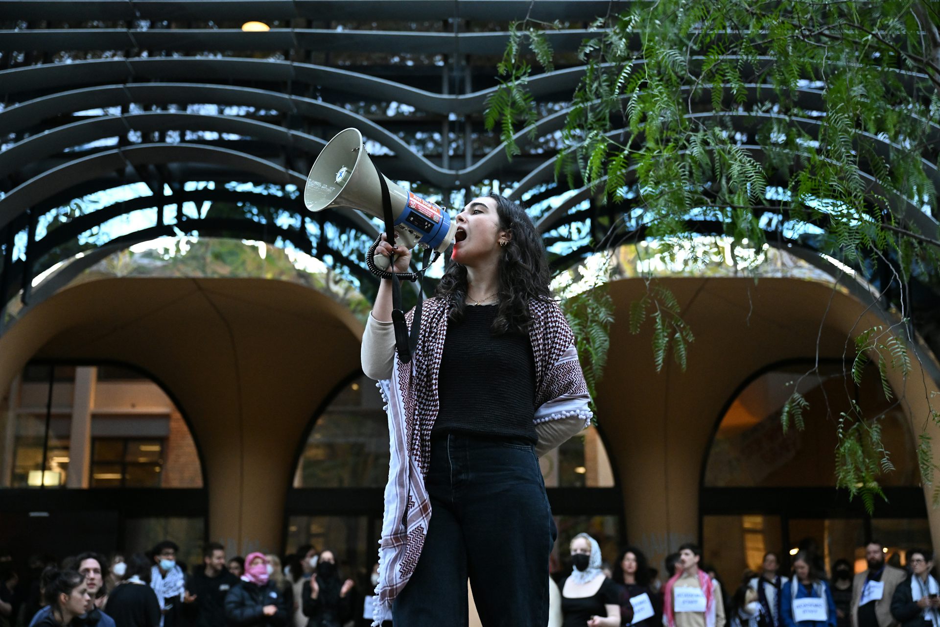 A woman stands at a university and speaks into a megaphone