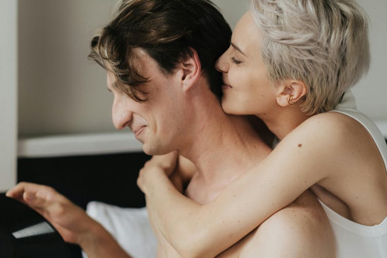 A woman happily embracing a man.