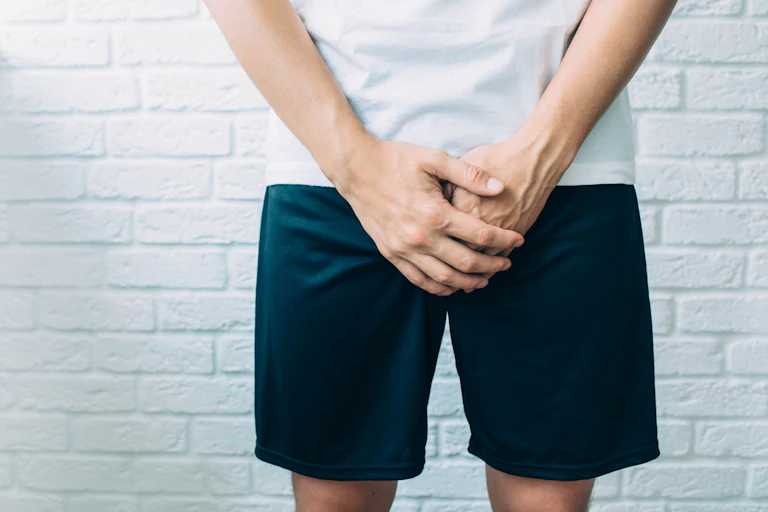 A man holding his hands over his crotch area.