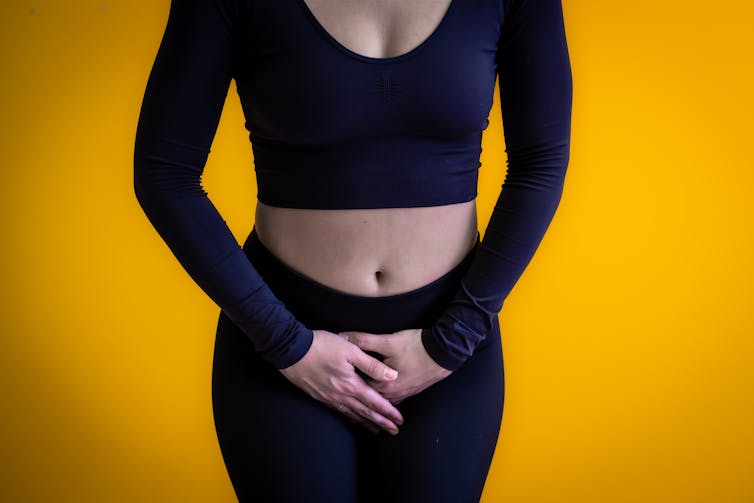 A woman holding her crotch area.