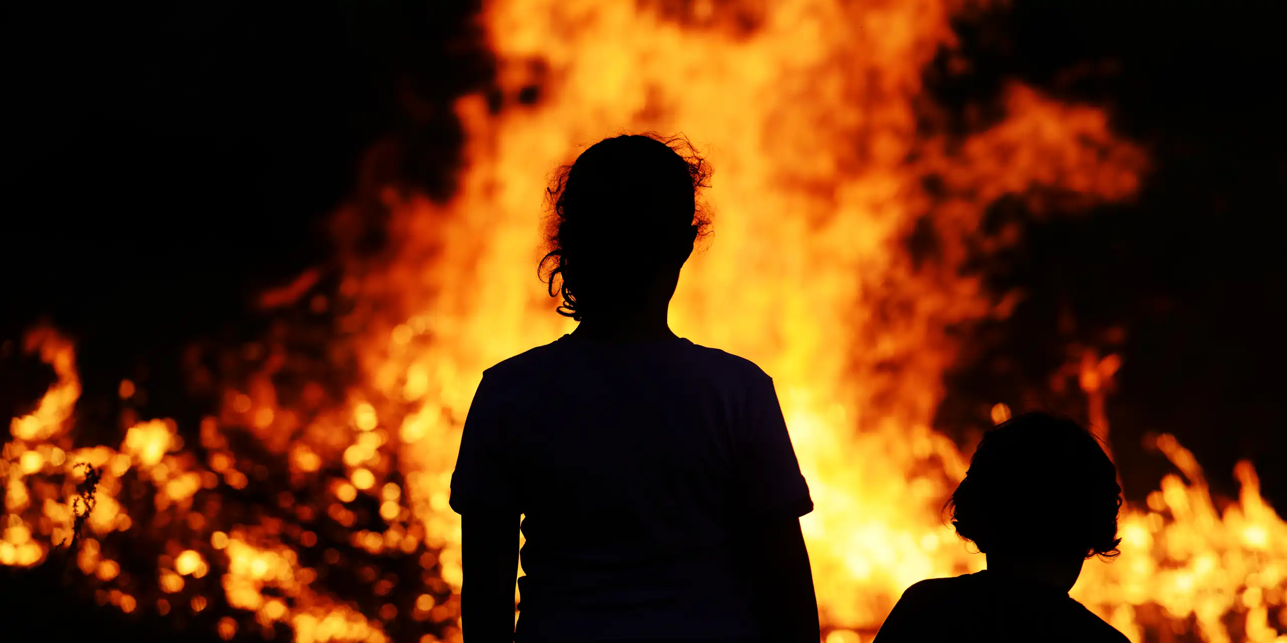 Deux personnes regardent, sidérées, un feu de forêt.