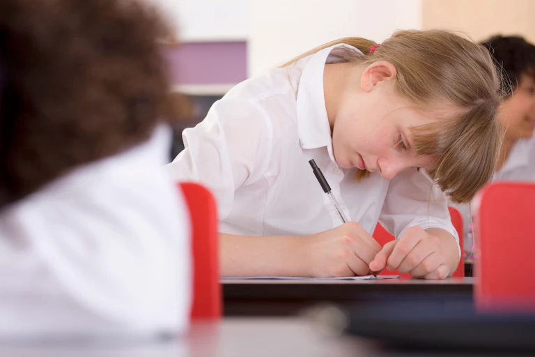 Girl in uniform writing with pen