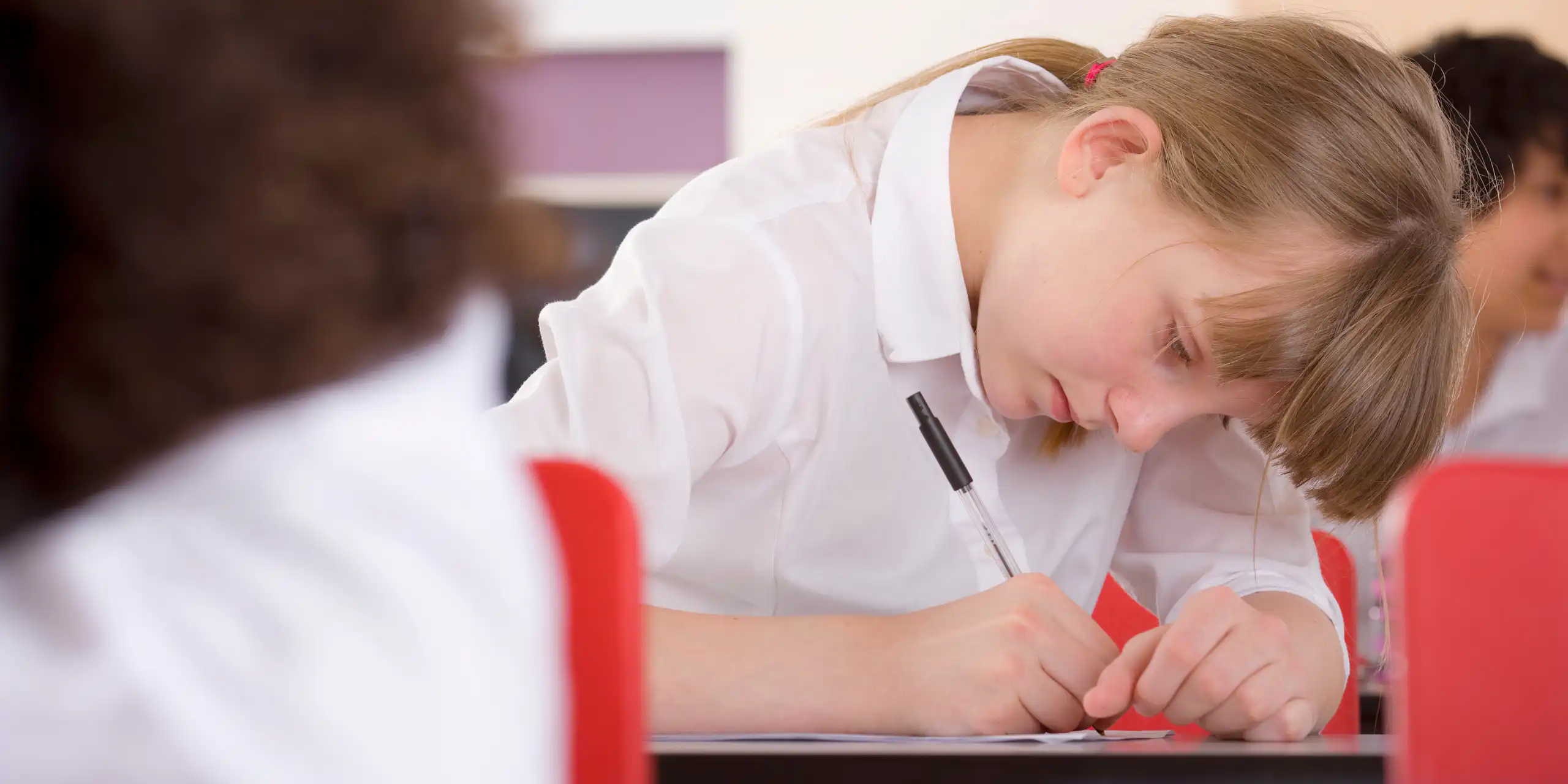 Girl in uniform writing with pen