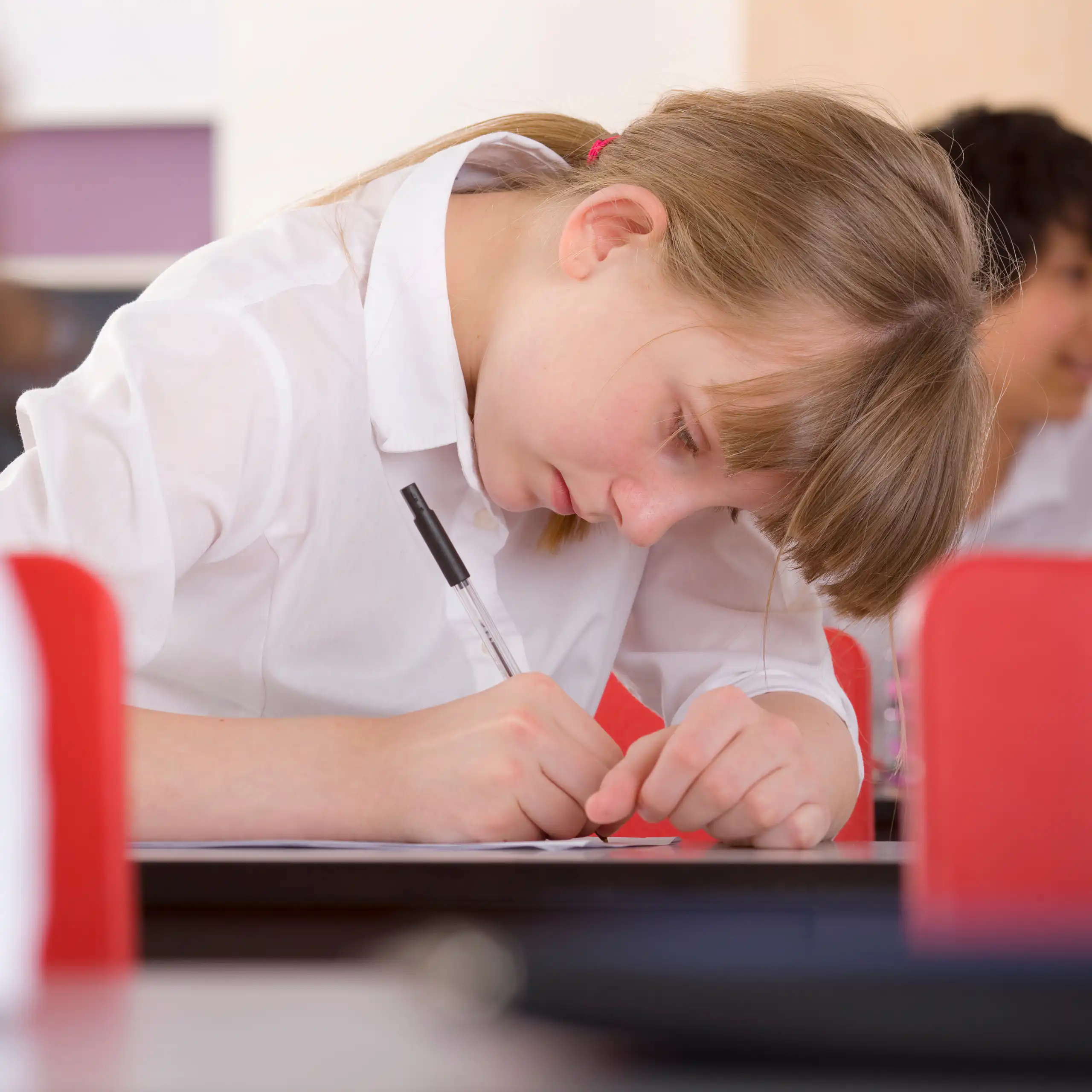 Girl in uniform writing with pen