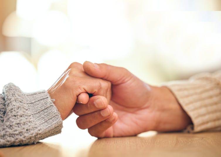 Close up of two hands holding and resting on a table