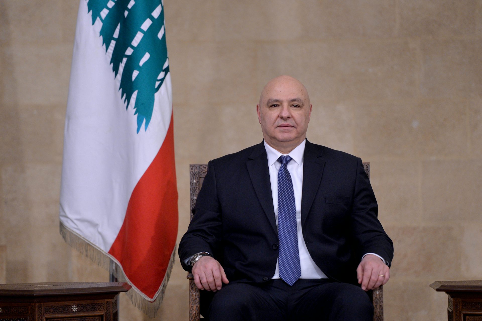 Joseph Aoun posing for a picture next to Lebanon's flag.