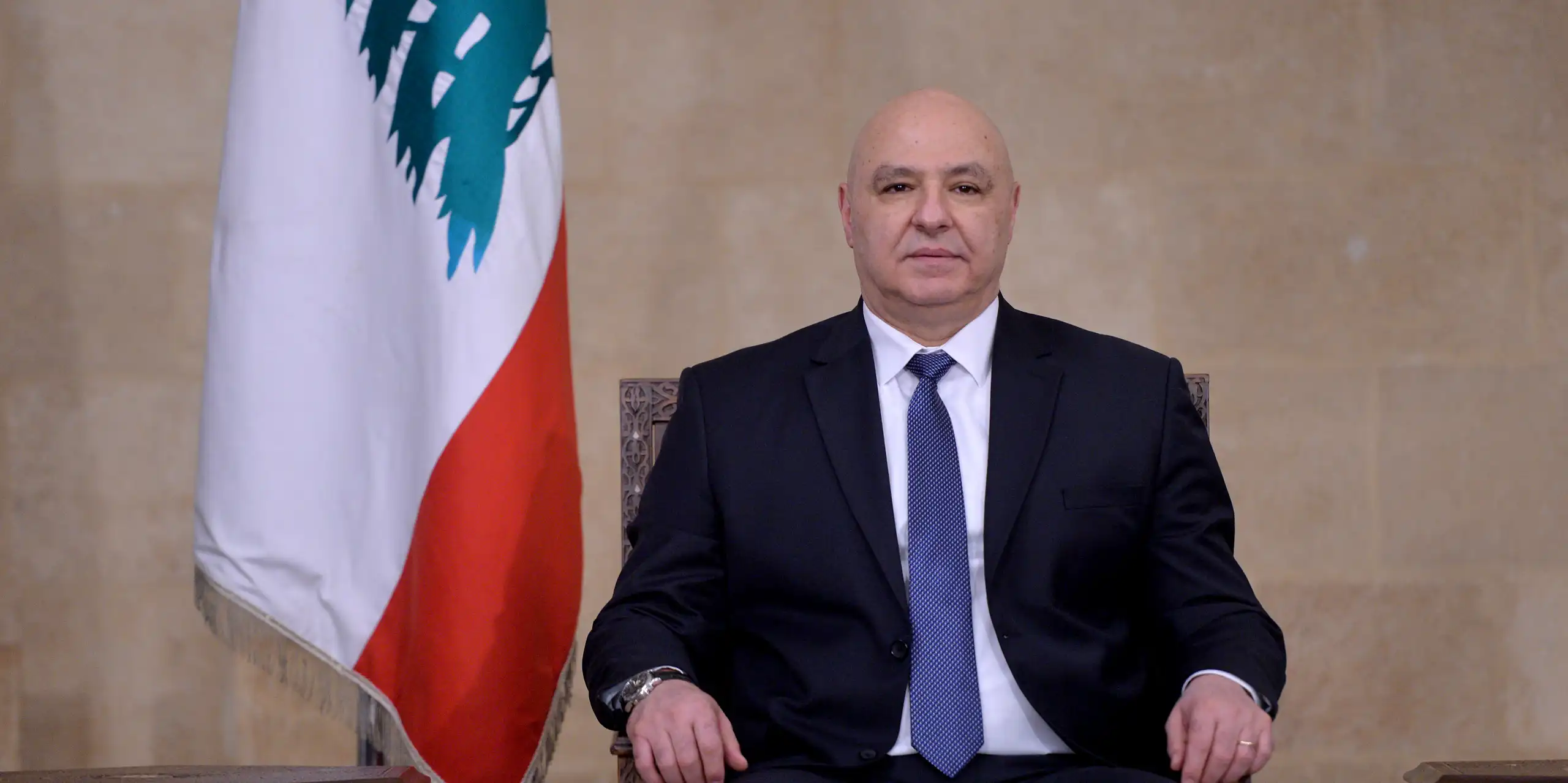 Joseph Aoun posing for a picture next to Lebanon's flag.