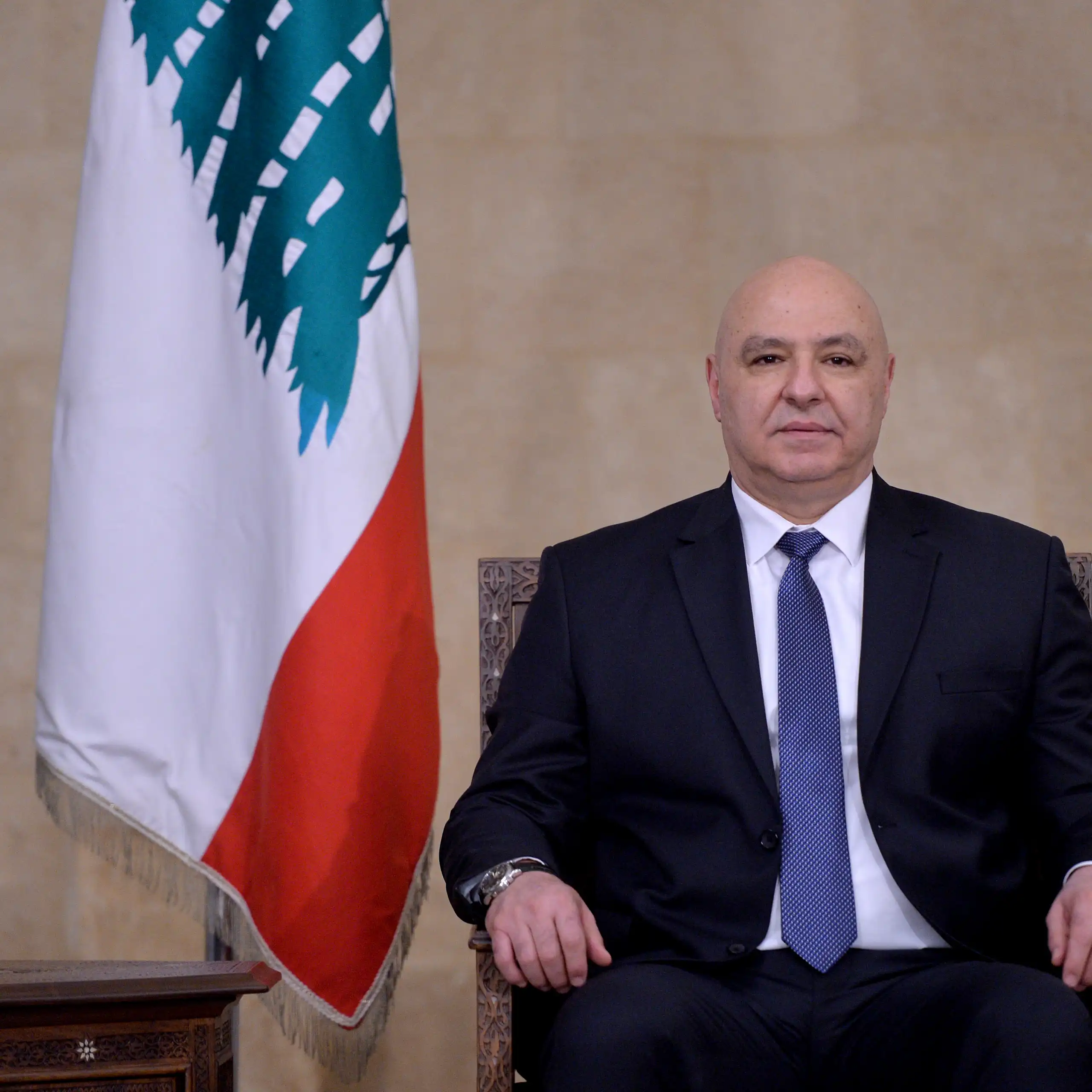 Joseph Aoun posing for a picture next to Lebanon's flag.