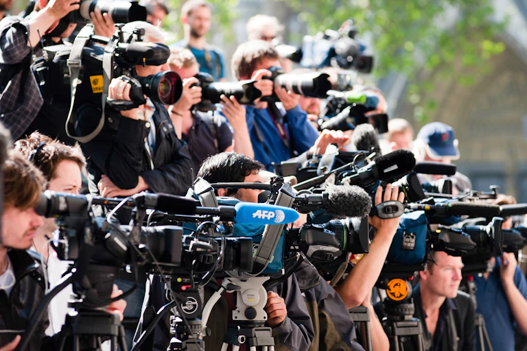 A crowd of reporters with cameras and microphones