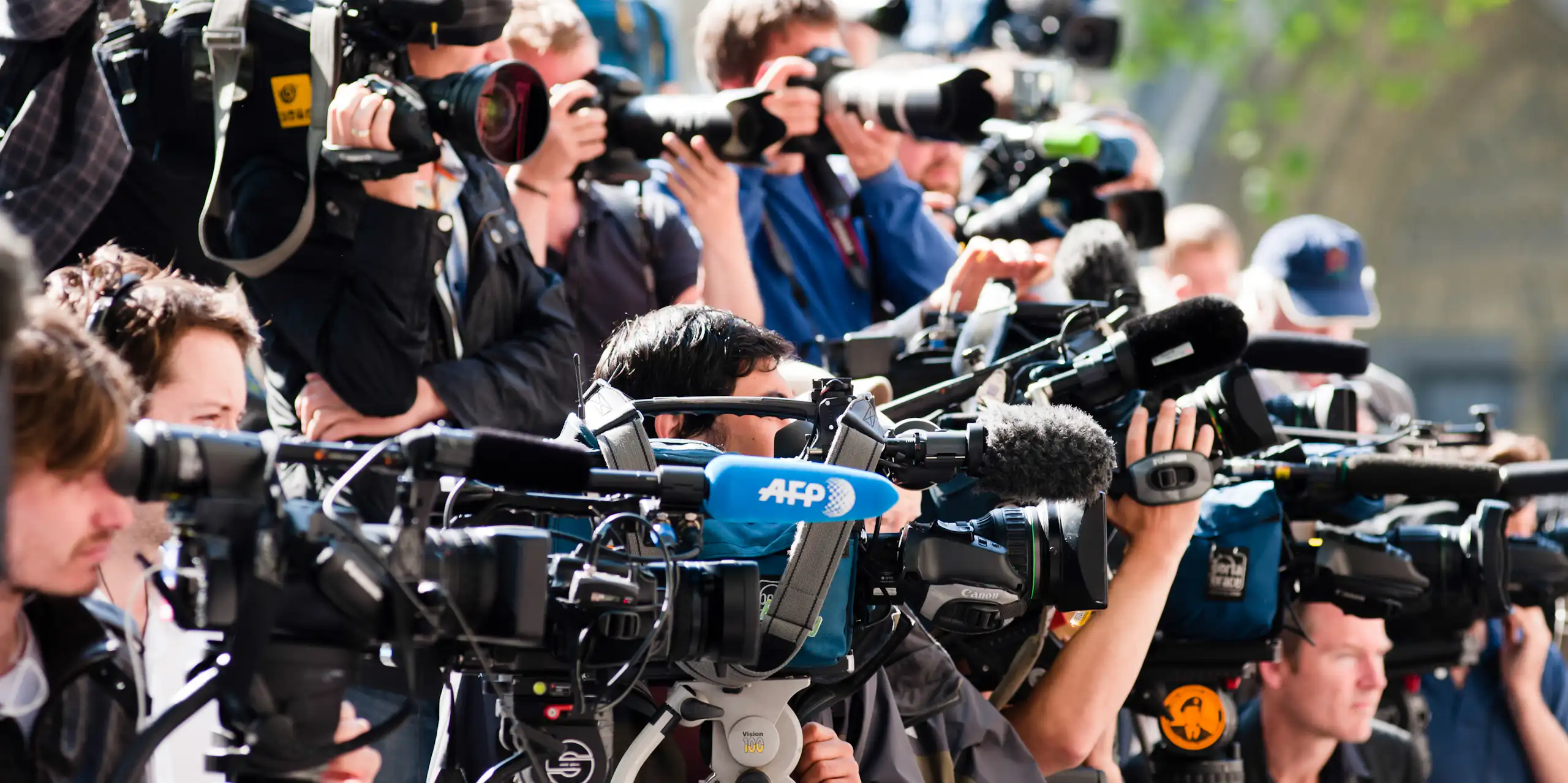 A crowd of reporters with cameras and microphones