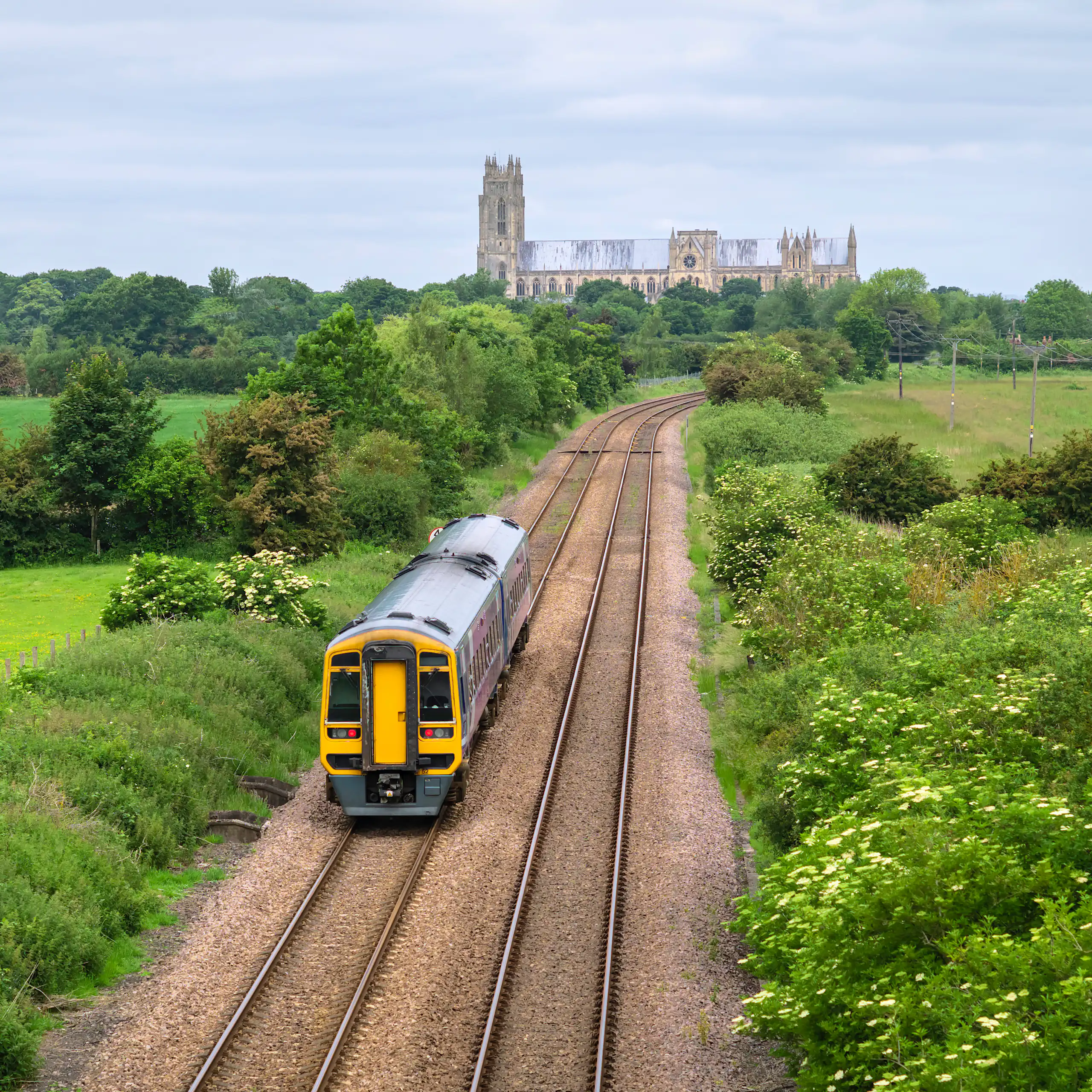 Train on tracks flanked by fields with church in background.