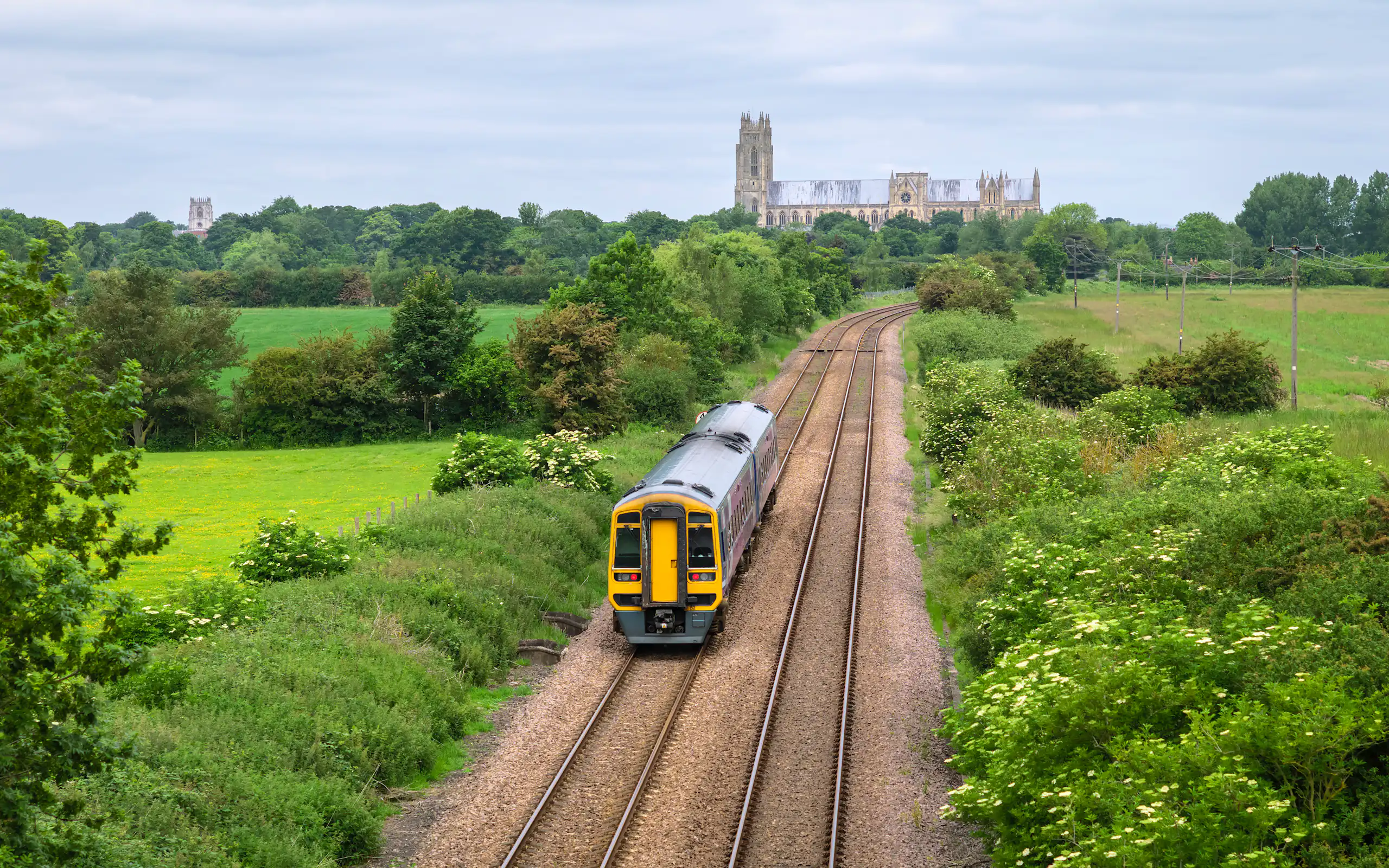 Train on tracks flanked by fields with church in background.