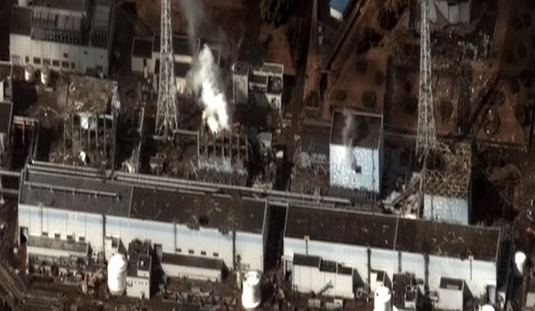Aerial photo of four square buildings, two of them emitting vapor plumes