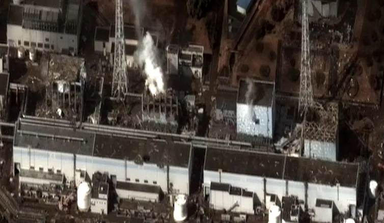 Aerial photo of four square buildings, two of them emitting vapor plumes