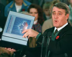 A man in a suit holds up a free-trade agreement.