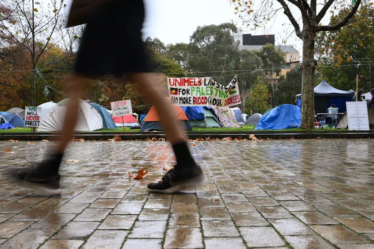 A person walks past a protest on a university campus