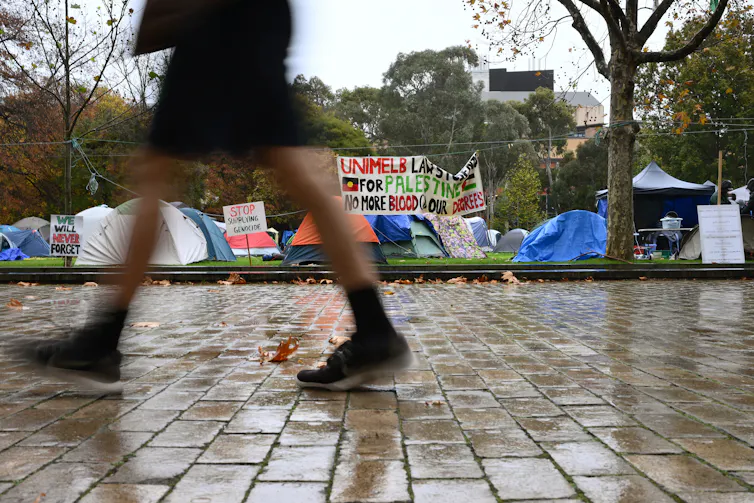 A person walks past a protest on a university campus