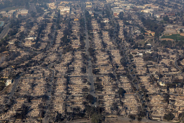 A devastated neighborhood retains its street grid but appears to have no houses standing.