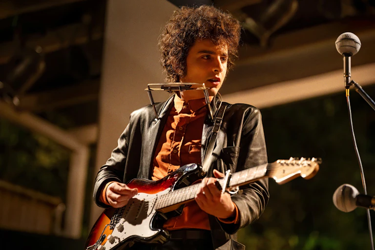 Film still: Dylan plays guitar.