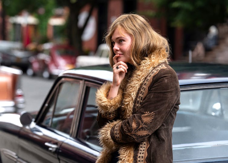 Film Still: Sylvie leans against a car.