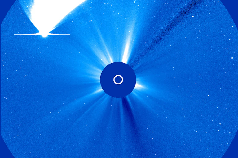 Image from a scientific instrument showing a brightly glowing object travelling past an even brighter obscured object in the centre of a circle.
