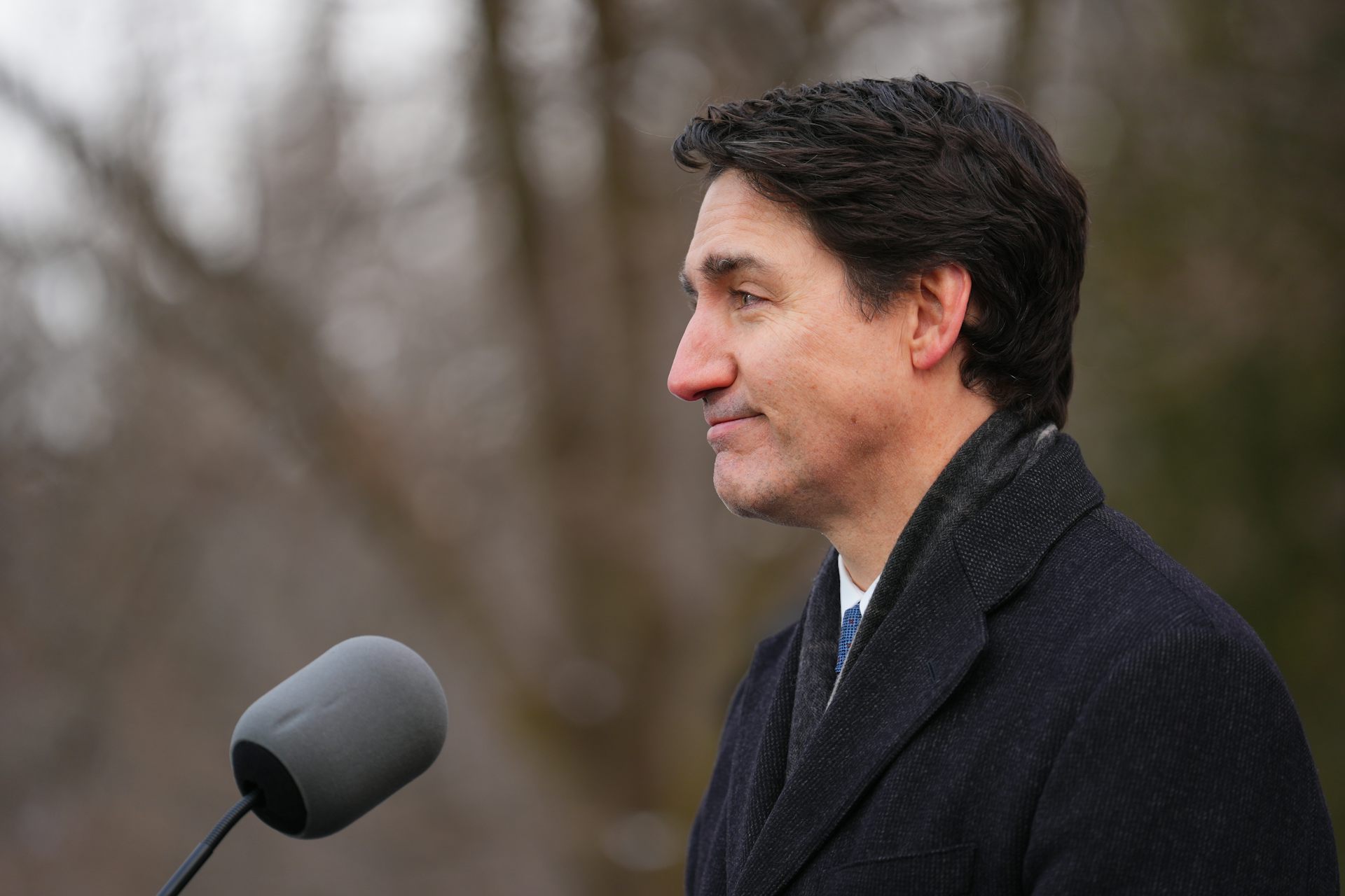 A dark-haired man seen in profile in front of a microphone