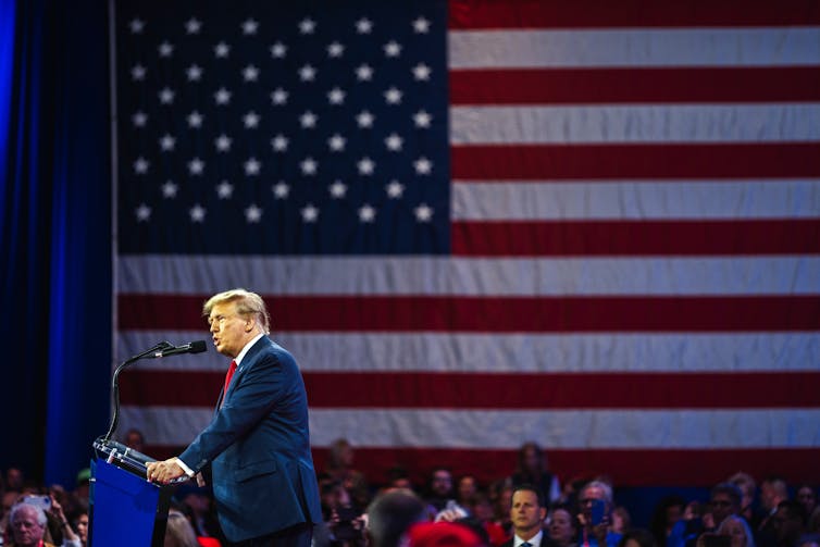 Donald Trump at lectern in front of US flag.