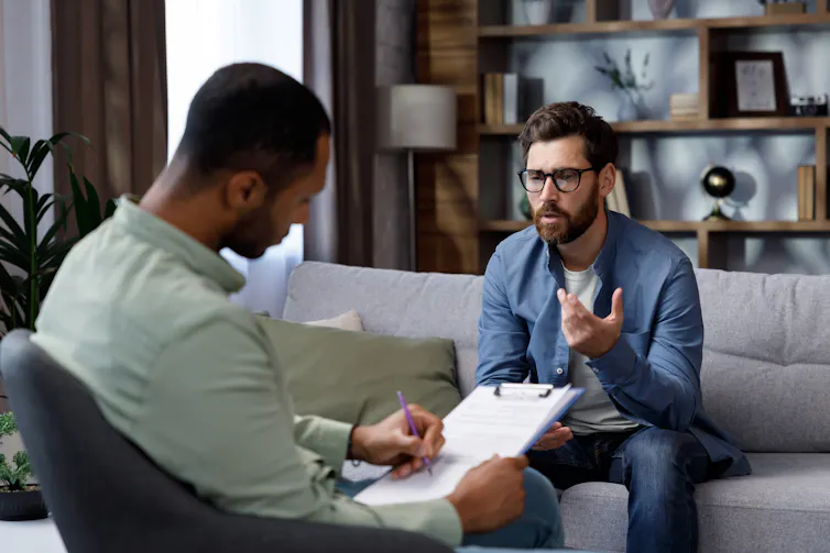 A man sits on a couch and talks to a psychotherapist.