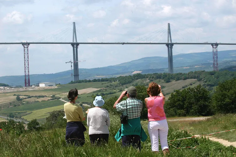 People look at large bridge with scaffolding