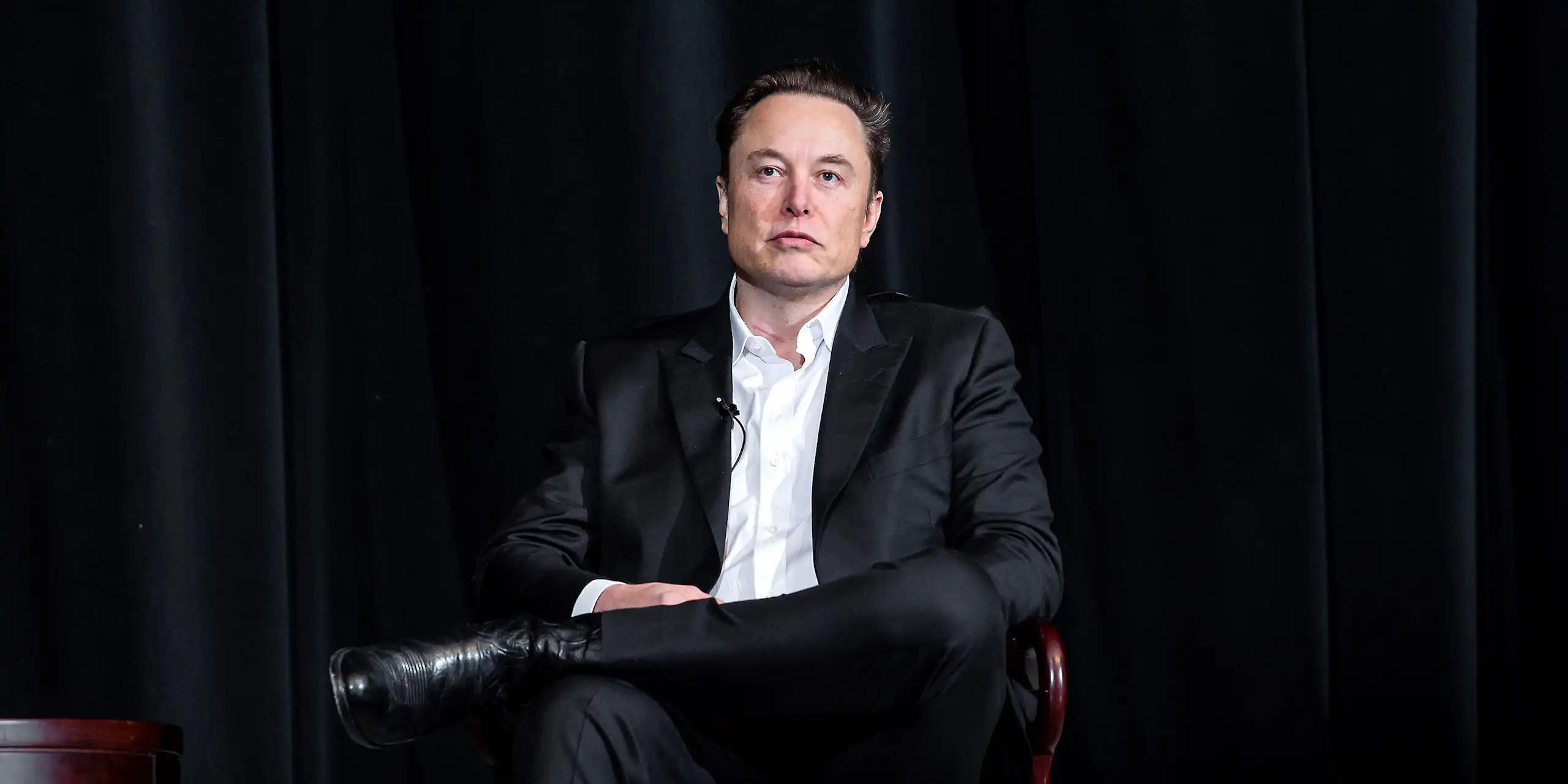 Elon Musk sitting in a chair.