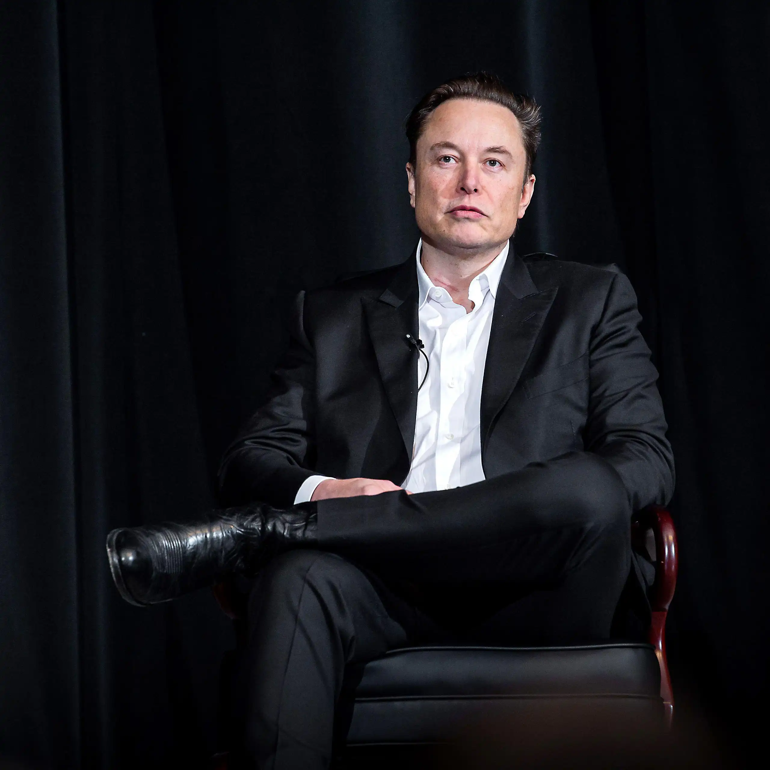 Elon Musk sitting in a chair.