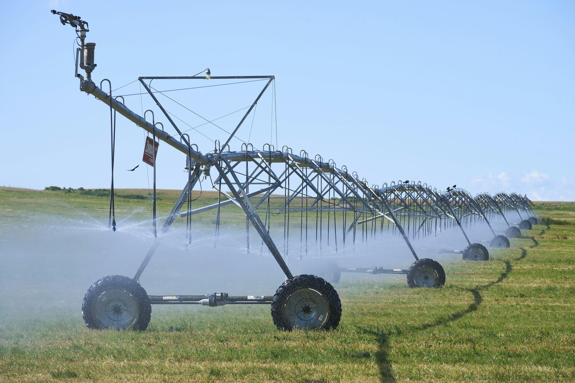 A large sprinkler irrigation system waters a farmer's field.