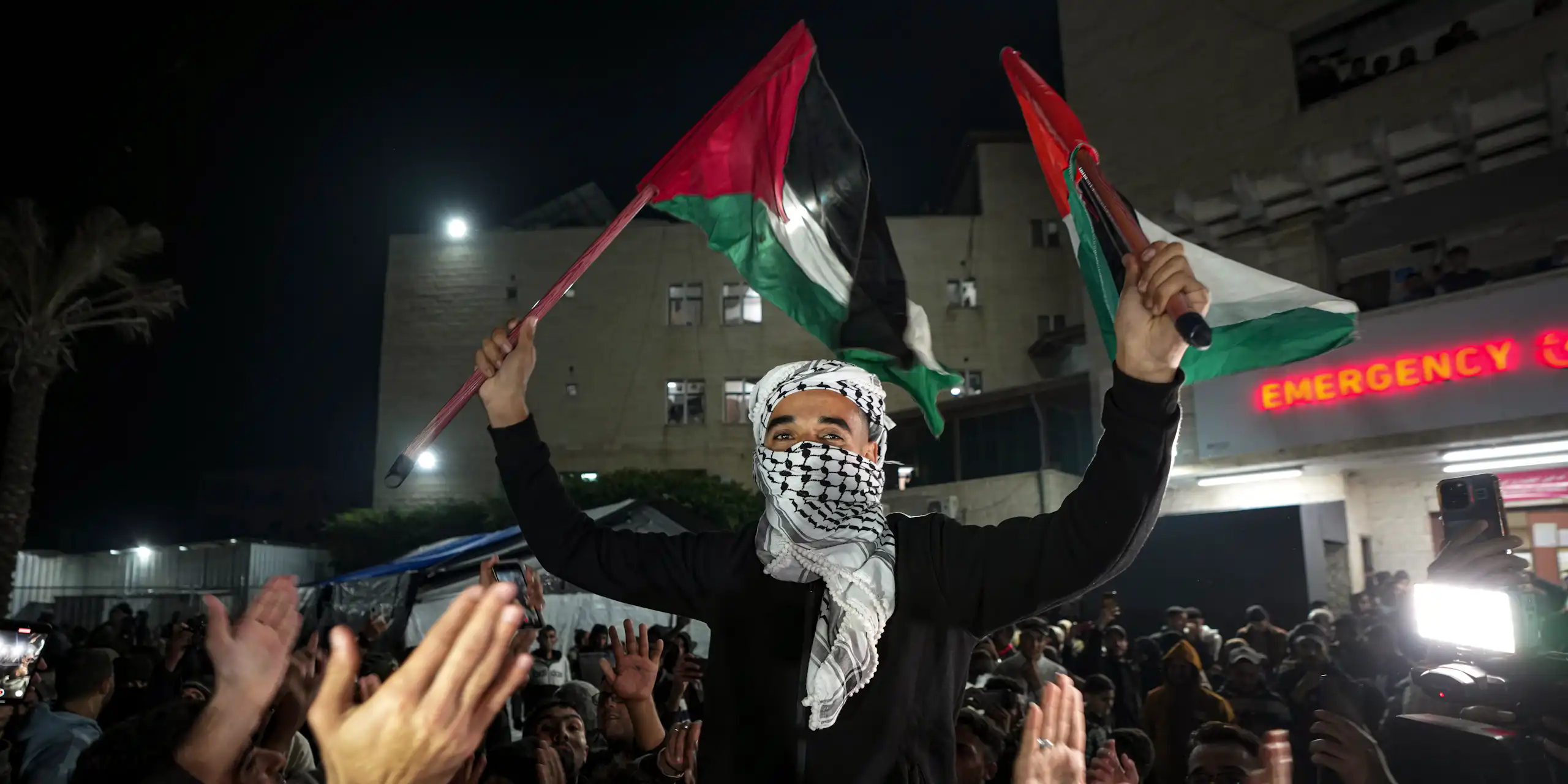 A Palestinian man celebrating and waving flags in a crowd