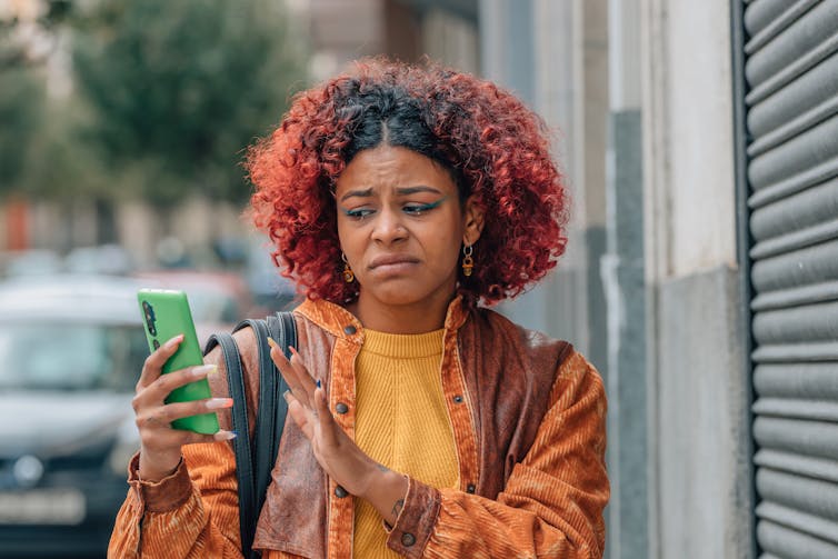AI Moves In as Young People Move On from Dating Apps 4 A woman grimaces while looking at a smartphone screen