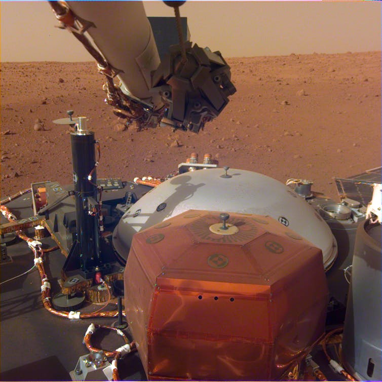 Photo of scientific instruments with the surface of Mars in the background.
