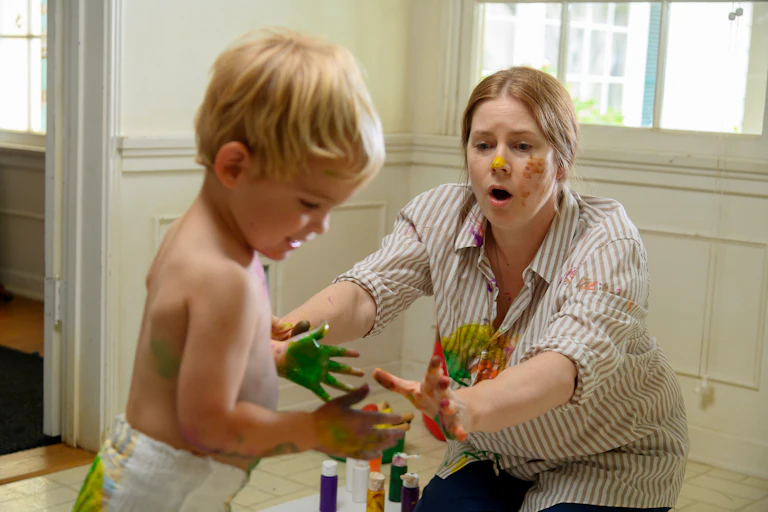 Film still: A mother and toddler covered in paint.