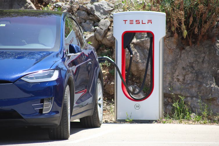 A parked blue car being recharged.