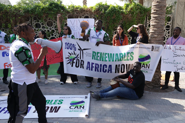 Protesters hold up a banner that says '100% renewables for Africa now'