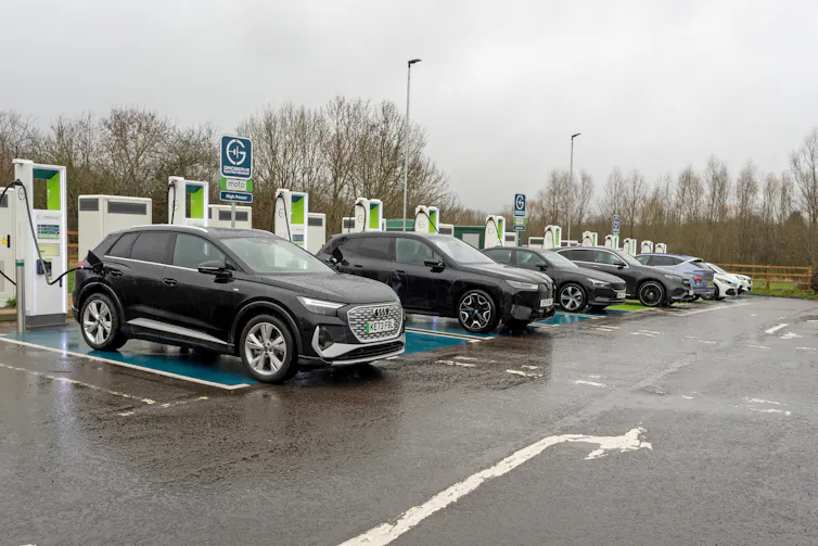 A row of electric cars plugged into public chargers.