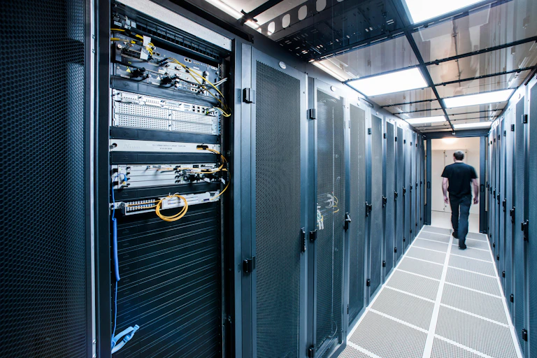 A person walks down a corridor with servers on either side.