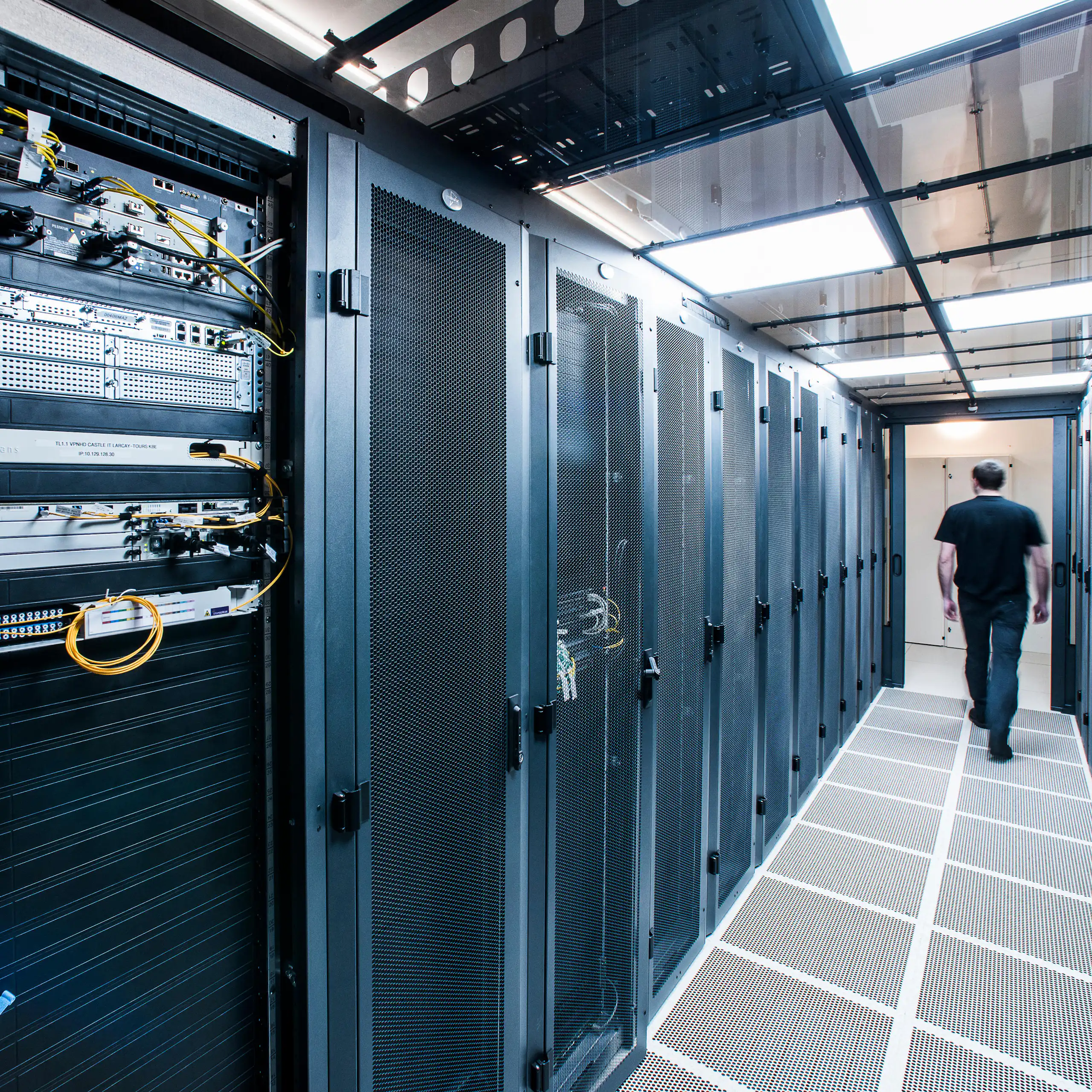 A person walks down a corridor with servers on either side.