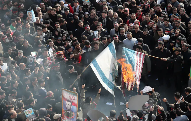 Iranians burn US and Israel flags during a funeral ceremony.