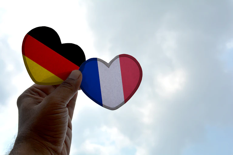 Une main sert deux cœurs avec les drapeaux allemands et français