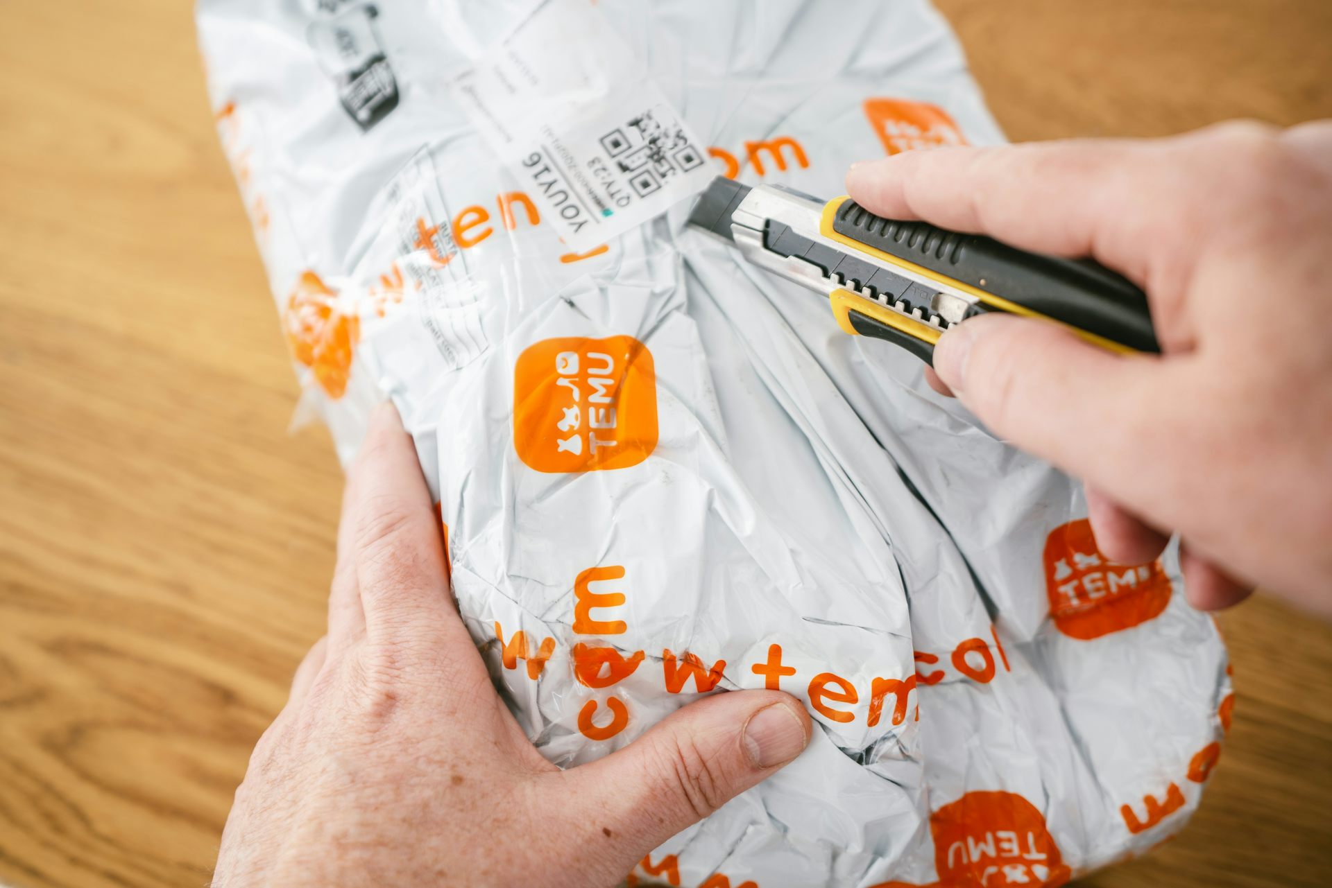 une personne ouvre un colis temu avec un cutter
