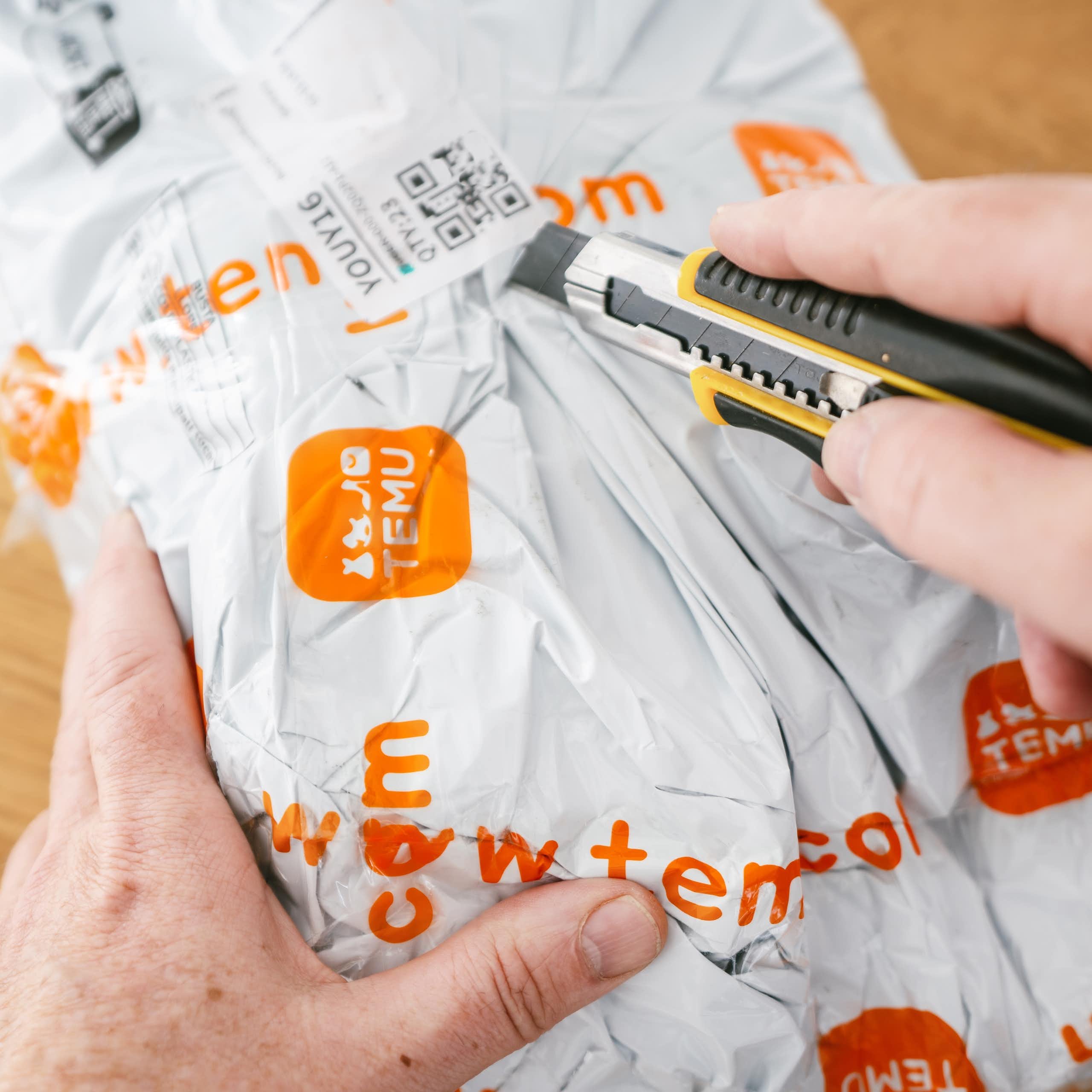 une personne ouvre un colis temu avec un cutter