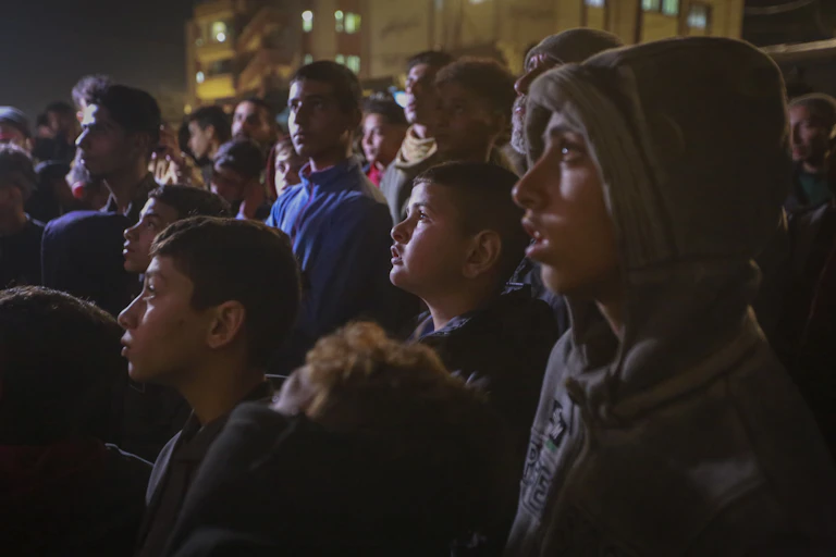 Um grupo de palestinos assiste a uma TV