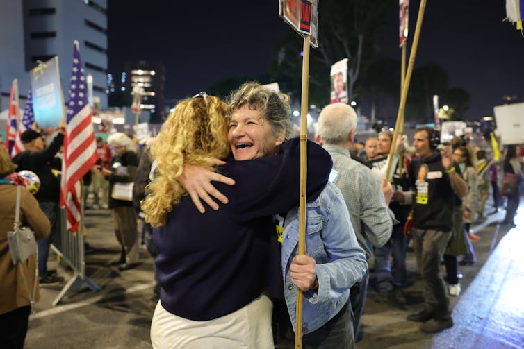 Two Israeli citizens hug as the news of a ceasefire and the release of Isreali hostages is announced.