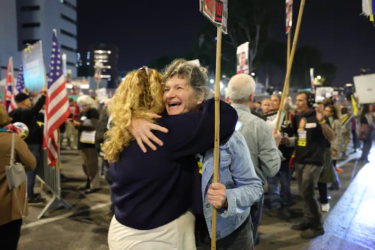 Two Israeli citizens hug as the news of a ceasefire and the release of Isreali hostages is announced.