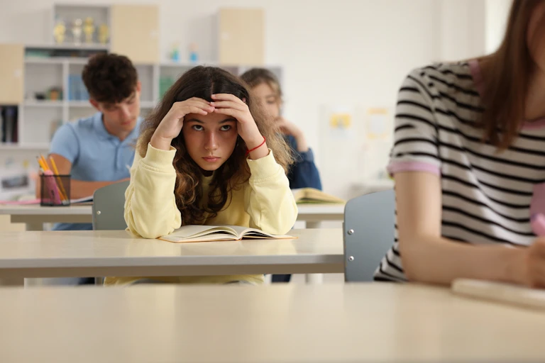 Une élève qui se prend la tête dans les mains en classe